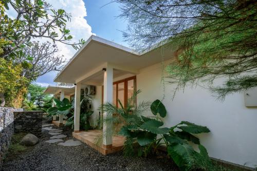 a house with white walls and trees at Sumberkima Resort in Pemuteran