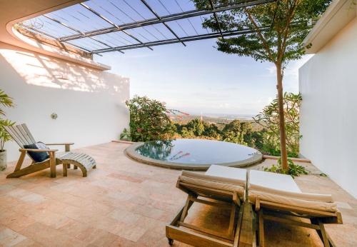 a patio with a hot tub and two chairs at Sumberkima Resort in Pemuteran