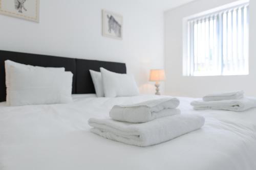 a white bed with white towels on it at Adbolton House Apartments - Sleek, Stylish, Brand New & Low Carbon in Nottingham