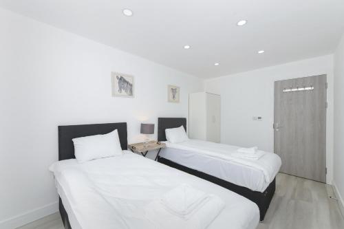two beds in a room with white walls at Adbolton House Apartments - Sleek, Stylish, Brand New & Low Carbon in Nottingham