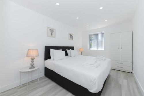 a white bedroom with a large white bed and a table at Adbolton House Apartments - Sleek, Stylish, Brand New & Low Carbon in Nottingham