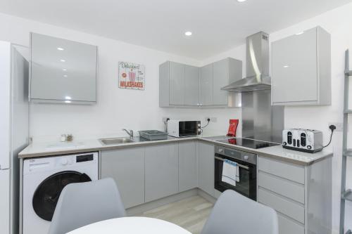 a kitchen with white appliances and white cabinets at Adbolton House Apartments - Sleek, Stylish, Brand New & Low Carbon in Nottingham