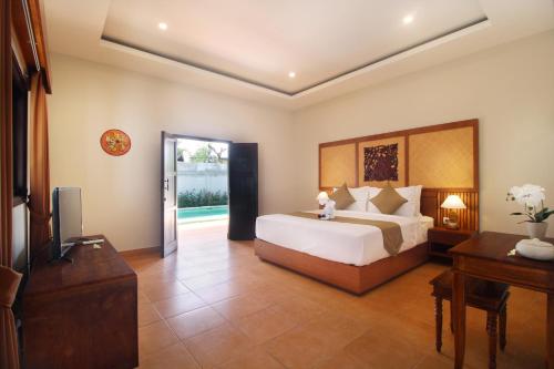 Un dormitorio con una cama y un televisor en una habitación. en Sudha Villa Bali B, en Seminyak