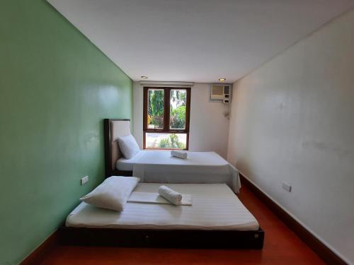 2 Betten in einem Zimmer mit Fenster in der Unterkunft Estancia De Lorenzo Tarlac in Tarlac City