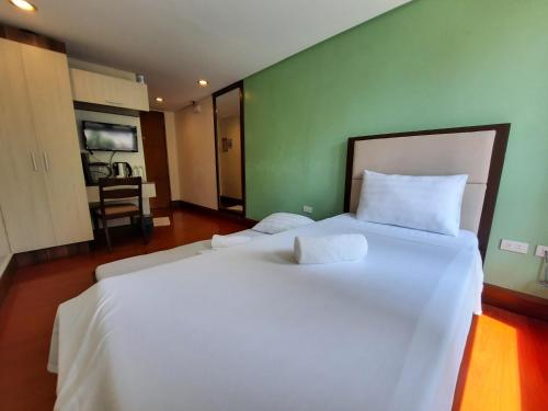 a large white bed in a room with a green wall at Estancia De Lorenzo Tarlac in Tarlac