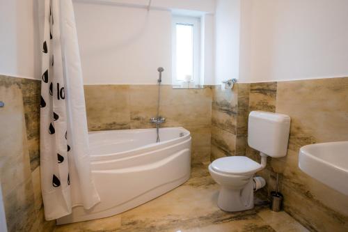 a bathroom with a tub and a toilet and a sink at HOME FOR SEVEN in Mamaia Sat/Năvodari