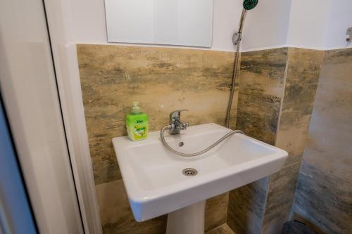 a bathroom sink with a green soap bottle on it at HOME FOR SEVEN in Mamaia Nord