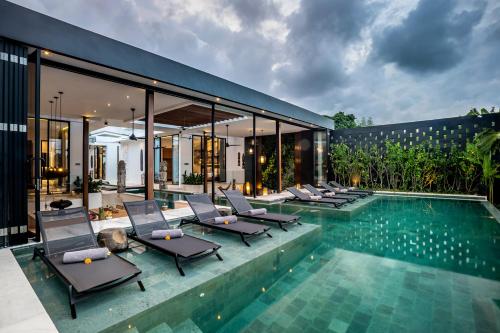 a villa with a swimming pool and lounge chairs at Villa Australis in Kerobokan