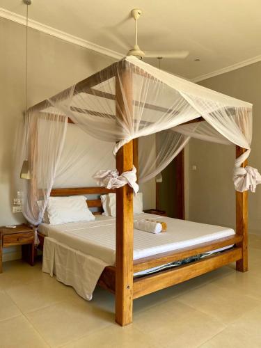 a bedroom with a wooden bed with a canopy at Paje Beach Apartments & Hotel in Paje