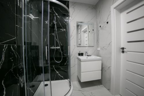 La salle de bains en noir et blanc est pourvue d'une douche et d'un lavabo. dans l'établissement Oxygen apartament nr 4, à Mielec