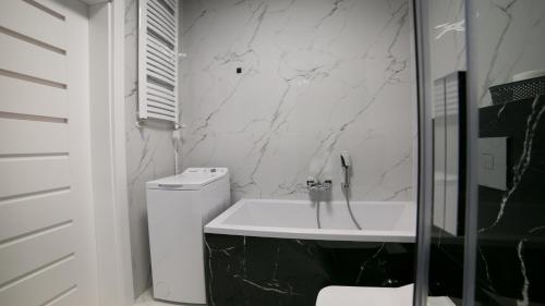 a bathroom with a white toilet and a marble wall at Oxygen apartament nr 4 in Mielec