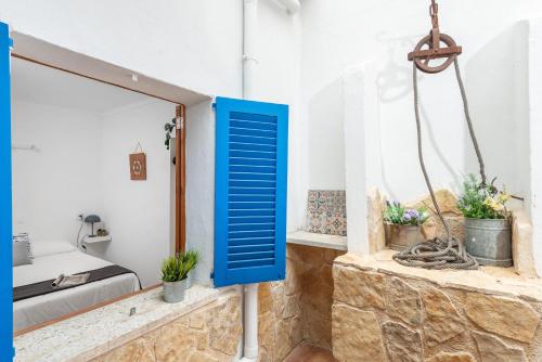a blue shutter in a room with a bed and plants at Sa Marineta in Porto Cristo