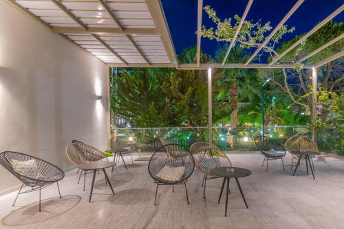 a patio with chairs and tables and a large window at Katerina Palace Hotel in Argasi