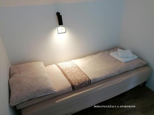 a bed in a room with a light on the wall at Nikolića kuća in Mitrovac