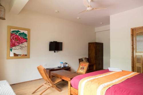 a bedroom with a bed and a table and a tv at Sparsh Resort, A Boutique Stay - Just 2kms uphill from Mall Road, near Old Manali in Manāli
