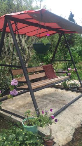 a swing with a red umbrella and some flowers at Dito House in K'obulet'i