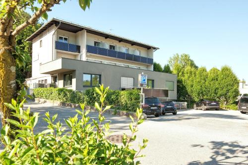 a building with cars parked in a parking lot at Hotel Velden - 24 Checkin Zimmer im Zentrum in Velden am Wörthersee