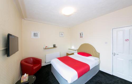 a hotel room with a bed and a red chair at Homeleigh Hotel in Bradford