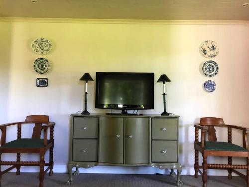 a tv sitting on top of a cabinet with two chairs at The Gables Guest House in Belfast