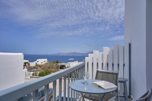 a table with a wine glass and a book on a balcony at Sofia Village in Mýkonos City
