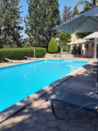 a blue swimming pool with an umbrella and chairs at Zena Holiday Villa in Pissouri