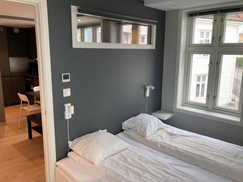 een slaapkamer met een bed en 2 ramen en een spiegel bij Skansen Apartments in Bergen