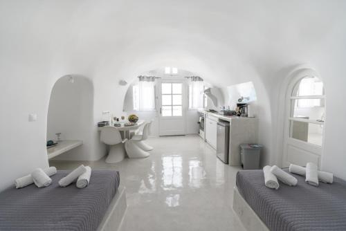 une chambre blanche avec deux lits et une cuisine dans l'établissement Fira-Cave-Sleeps 13-Parking-Pool-Pet Friendly, à Fira