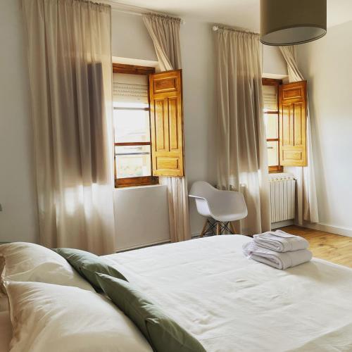 a bedroom with a bed with white sheets and a chair at El desván de Bruno in Villalobos