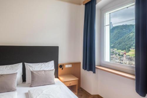 sypialnia z łóżkiem i dużym oknem w obiekcie Villa Martiner Apartments Francesco w mieście Ortisei