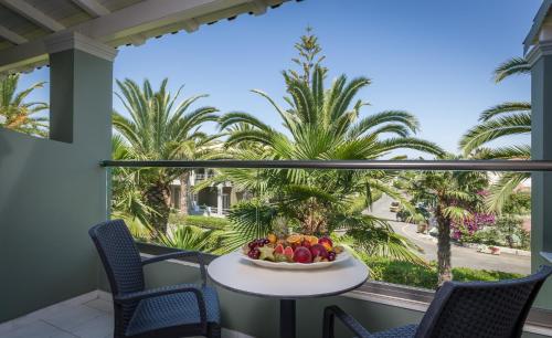 a table with fruit on a balcony with palm trees at Acharavi Beach Hotel in Acharavi