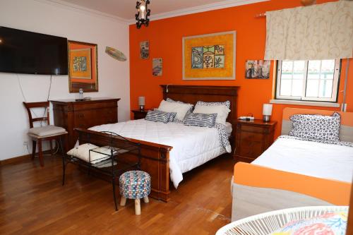 1 dormitorio con 2 camas y pared de color naranja en Casa da Avó Bela, en Buarcos