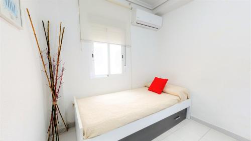 Habitación blanca pequeña con cama con almohada roja en El Encanto de Cordoba (Parking incluido), en Córdoba