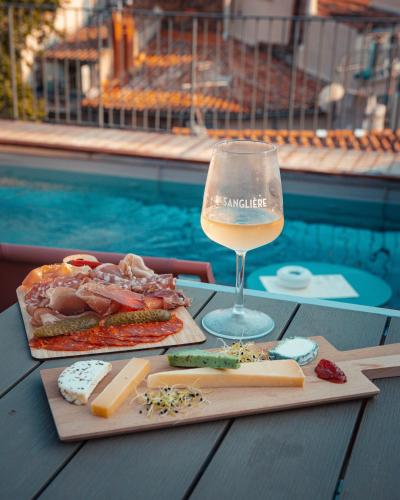 a glass of wine and food on a table by a pool at Grand Hôtel Dauphiné Toulon, Boutique Hôtel & Suites in Toulon