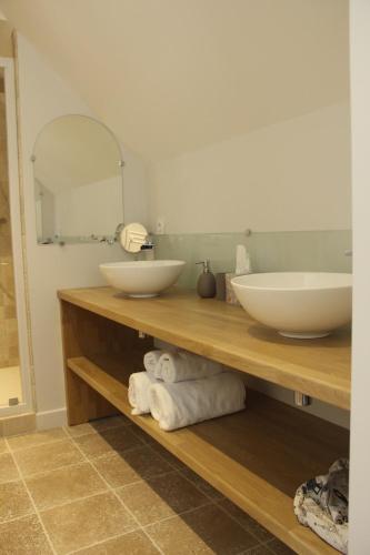 a bathroom with a counter with two sinks and towels at L'Audacieuse in Behuard