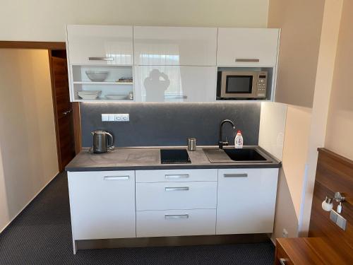 a white kitchen with a sink and a microwave at Apartmány wellness Frymburk in Frymburk