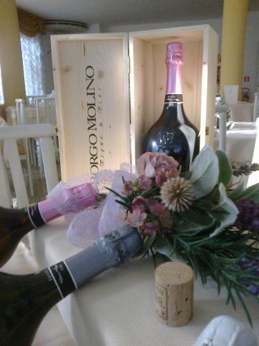 a bottle of wine and a bottle of flowers at Hotel Villa Luisa in Lignano Sabbiadoro