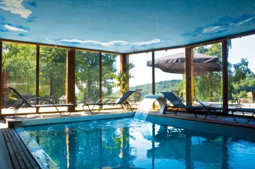 einen Pool mit Stühlen und einem Sonnenschirm in der Unterkunft Le Gîte du Donon in Grandfontaine
