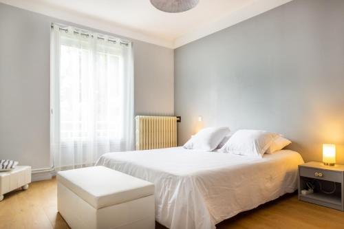 een witte slaapkamer met een wit bed en een raam bij L'appartement à Cardaillac in Rodez