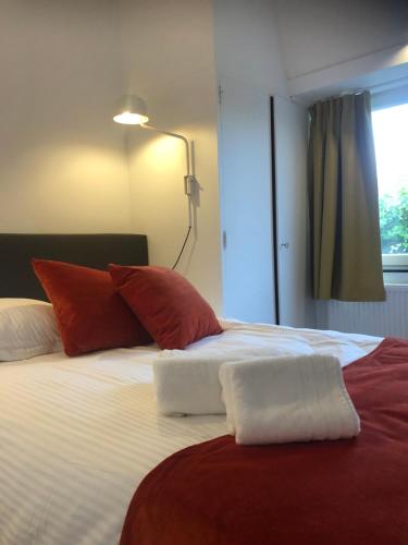 ein Bett mit roten und weißen Kissen und einer Lampe in der Unterkunft duunn2 in Koksijde