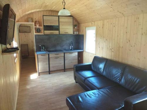 a living room with a leather couch and a kitchen at Osada nad żurawim stawem in Krzywogoniec