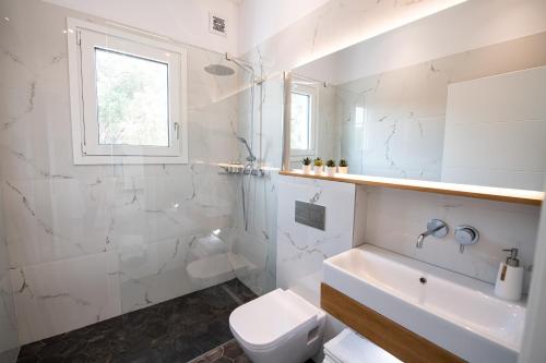 a white bathroom with a toilet and a sink at Summer Vibes Tsoukalades in Tsoukaladhes