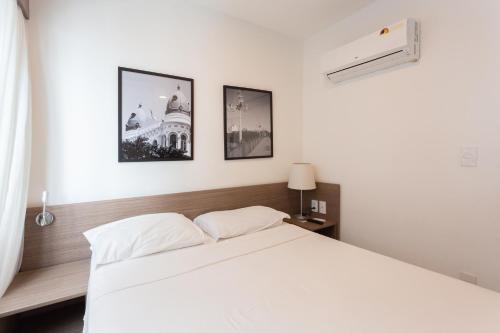 a bedroom with a white bed and three pictures on the wall at Beach Class Santa Maria by Easy Home in Recife
