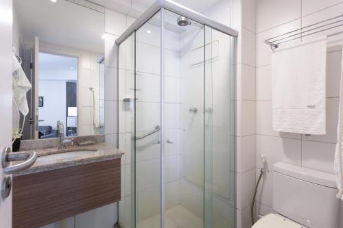 a bathroom with a glass shower and a sink at Beach Class Santa Maria by Easy Home in Recife