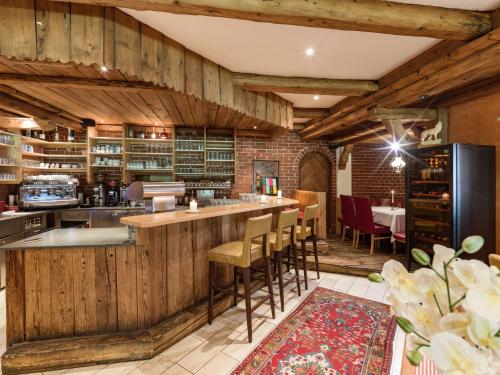 a kitchen with wooden walls and a bar with stools at Hotel Restaurant Sidan in Schwendau