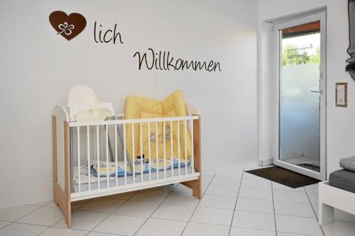 a baby crib in a white room with a sign that reads lick willuminati at Ferienwohnung Gartenblick an der Mainschleife in Schwarzach am Main
