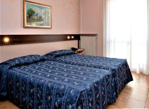 a bedroom with a blue bed with a blue comforter at Bes Hotel Papa San Pellegrino Terme in San Pellegrino Terme