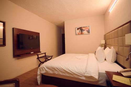a hotel room with a bed and a flat screen tv at Hotel King's Palace in Lubumbashi