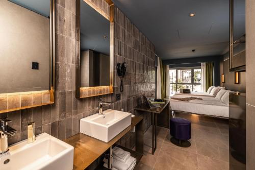 a bathroom with two sinks and a bed in the background at HD8 Hotel Milano in Milan