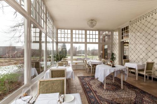 - un restaurant avec des tables, des chaises et de grandes fenêtres dans l'établissement Hotel Resort Landgoed Westerlee, à Westerlee