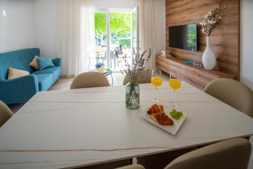 a white dining room table with two glasses of orange juice at Garden apartment in Pakoštane